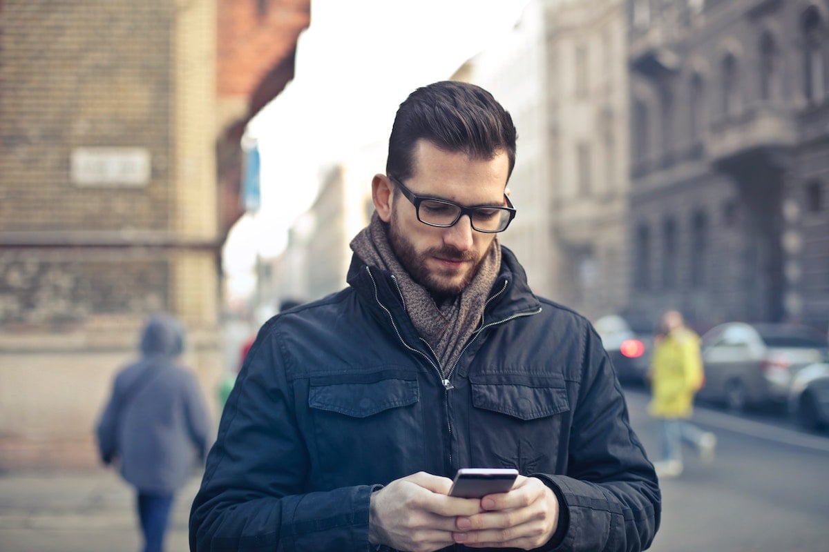 Man Wearing Black Jacket Looks at His Phone on a City Street Salsify Ecommerce Trends 2020