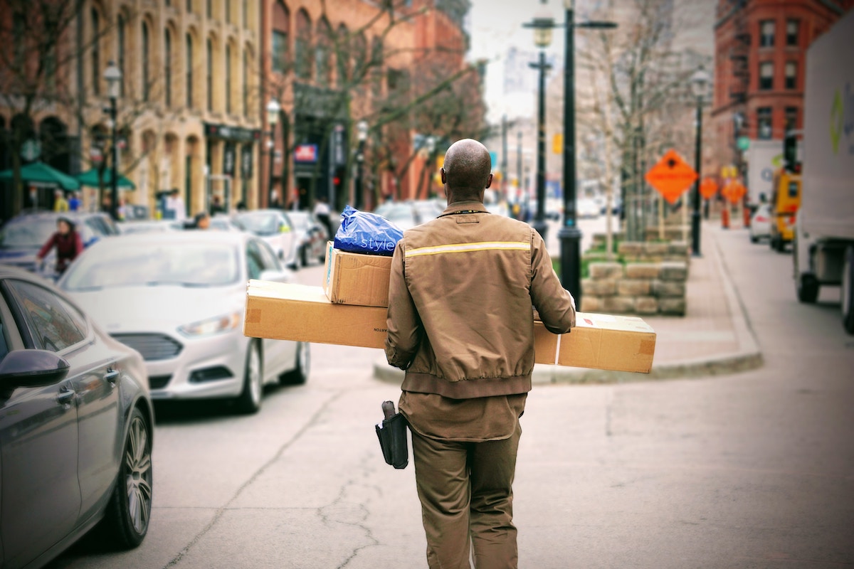 A Delivery Driver Holds Packages on a Busy City Street Salsify Brand Manufacturers Changing Ecommerce